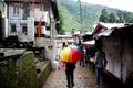 Young indian girl with a colorful umbrella in a busy market place street in McLeodganj