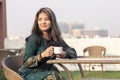 Young indian girl having tea or coffee in a roof top cafe, wearing indian traditional dress