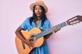 Young indian girl playing classical guitar winking looking at the camera with sexy expression, cheerful and happy face