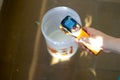 Young indian girl taking the temperature of a compound in a plastic jar with an infrared thermometer for soap making