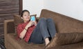 Young indian girl using her mobile phone while lying on the couch. Young generation using mobile phone. Mobile and technology Royalty Free Stock Photo