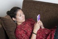 Young indian girl using her mobile phone while lying down on the couch.Lifestyle and technology concept Royalty Free Stock Photo