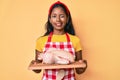 Young indian girl wearing cook apron and holding chicken winking looking at the camera with sexy expression, cheerful and happy Royalty Free Stock Photo