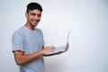 Young Indian handsome boy smiling into the camera while holding his laptop in his arms