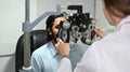 Young Indian male patient checking eye vision with phoropter eyesight measurement testing machine in clinic Royalty Free Stock Photo