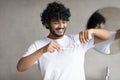 Young indian man applying toothpaste on toothbrush, brushing teeth in the morning, standing in bathroom, copy space Royalty Free Stock Photo