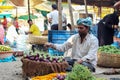 A young Indian man arranging brinjals neatly in a wicker basket for selling in the local vegetable market