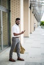 Young Indian Man with beard traveling carrying leather bag, walking on street talking on cell phone Royalty Free Stock Photo