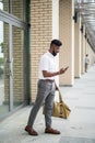 Young Indian Man with beard traveling carrying leather bag, walking on street talking on cell phone Royalty Free Stock Photo