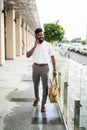 Young Indian Man with beard traveling carrying leather bag, walking on street talking on cell phone Royalty Free Stock Photo