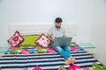 Young indian man busy working on his laptop doing office work while relaxing on bed in bedroom, freelancer working from home. Royalty Free Stock Photo