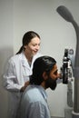 Young Indian man checking eyesight on auto refractor in ophthalmologist clinic. Eye health check and ophthalmology Royalty Free Stock Photo