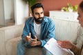 Young Indian man consulting with professional psychologist sitting indoor Royalty Free Stock Photo