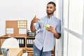 Young indian man drinking a cup coffee at the office pointing finger to one self smiling happy and proud Royalty Free Stock Photo