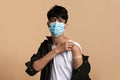 Young indian man in face mask showing he got vaccinated