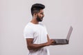 Young indian handsome man holding laptop standing on white background