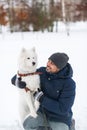 Young indian man and solid white fluffy dog in winter day. Royalty Free Stock Photo