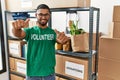 Young indian man volunteer holding donations box approving doing positive gesture with hand, thumbs up smiling and happy for Royalty Free Stock Photo
