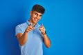 Young indian man wearing casual polo standing over isolated blue background pointing fingers to camera with happy and funny face Royalty Free Stock Photo