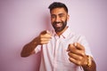 Young indian man wearing casual shirt standing over isolated pink background pointing fingers to camera with happy and funny face Royalty Free Stock Photo