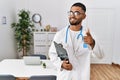 Young indian man wearing doctor uniform and stethoscope pointing fingers to camera with happy and funny face Royalty Free Stock Photo