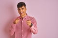 Young indian man wearing elegant shirt standing over isolated pink background pointing fingers to camera with happy and funny face Royalty Free Stock Photo