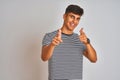 Young indian man wearing navy striped t-shirt standing over isolated white background pointing fingers to camera with happy and Royalty Free Stock Photo