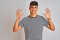 Young indian man wearing navy striped t-shirt standing over isolated white background showing and pointing up with fingers number Royalty Free Stock Photo