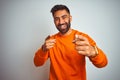 Young indian man wearing orange sweater over isolated white background pointing fingers to camera with happy and funny face Royalty Free Stock Photo