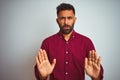 Young indian man wearing red elegant shirt standing over isolated grey background Moving away hands palms showing refusal and Royalty Free Stock Photo