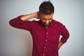 Young indian man wearing red elegant shirt standing over isolated grey background Suffering of neck ache injury, touching neck