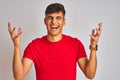 Young indian man wearing red t-shirt standing over isolated white background celebrating mad and crazy for success with arms Royalty Free Stock Photo
