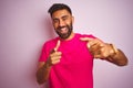 Young indian man wearing t-shirt standing over isolated pink background pointing fingers to camera with happy and funny face Royalty Free Stock Photo