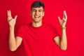 Young indian man wearing t-shirt standing over isolated red background celebrating mad and crazy for success with arms raised and Royalty Free Stock Photo