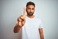 Young indian man wearing t-shirt standing over isolated white background Pointing with finger up and angry expression, showing no Royalty Free Stock Photo