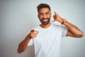 Young indian man wearing t-shirt standing over isolated white background smiling doing talking on the telephone gesture and Royalty Free Stock Photo