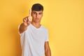 Young indian man wearing white t-shirt standing over isolated yellow background Pointing with finger up and angry expression, Royalty Free Stock Photo