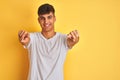 Young indian man wearing white t-shirt standing over isolated yellow background pointing to you and the camera with fingers, Royalty Free Stock Photo