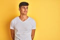 Young indian man wearing white t-shirt standing over isolated yellow background smiling looking to the side and staring away Royalty Free Stock Photo