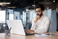 A young Indian man is working in the office on a laptop, thoughtfully and seriously looking at the screen. Reads Royalty Free Stock Photo