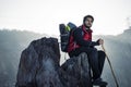 Young indian mountaineer sitting on the top of the mountain on a cliff with a backpack and a stick, enjoying the view from the top Royalty Free Stock Photo