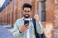 Young indian student received online win notification message phone, successful entrance exam results, man with backpack Royalty Free Stock Photo