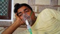 Young man infected with Covid 19 disease. Patient inhaling oxygen wearing mask with liquid Oxygen flow