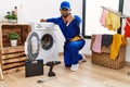 Young indian technician working on washing machine looking unhappy and angry showing rejection and negative with thumbs down