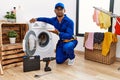 Young indian technician working on washing machine pointing aside with hands open palms showing copy space, presenting Royalty Free Stock Photo