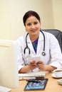 Young Indian traditional femal doctor texting at her desk