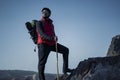 Young indian traveler hiking up the mountain with a backpack and a stick with a beautiful lake view in the background. Sports and