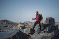 Young indian traveler standing confidently on top of the mountain over a cliff, wearing a red snow jacket. Confident and success Royalty Free Stock Photo