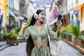 A young Indian woman dances on the street to the music she listens to in headphones from her phone. Standing outside on Royalty Free Stock Photo