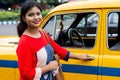 Young Indian woman opening gate of old yellow taxi Royalty Free Stock Photo